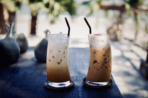 istock Iced cold coffee latte cappuccino summer refreshing drinks on wood table with blurred tropical palm trees beach background. 1144853097