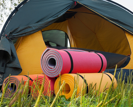 Open tent and rolled sleeping pads. Campsite.