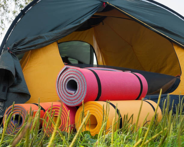 Open tent and rolled sleeping pads. Open tent and rolled sleeping pads. Campsite. beach mat stock pictures, royalty-free photos & images