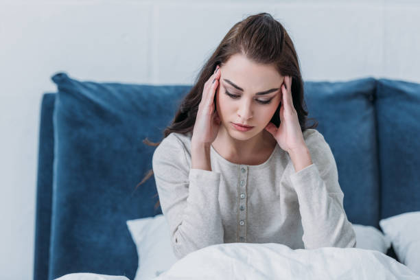 istock beautiful upset woman lying in bed and having headache 1144856593