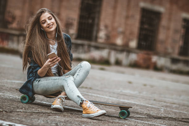 istock Female Skateboarder is Using a Mobile Phone in the Street 1144856771