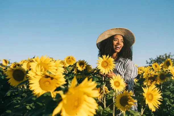 Photo of Happy young black woman in a sunflower field