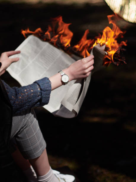 istock A woman with a clock on her hand is holding lit newspaper 1144859378