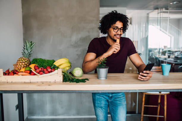 istock Man eating carrot and using phone 1144859784