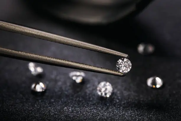 Photo of Gemstone clamped in tweezers. Jewelry inserts closeup