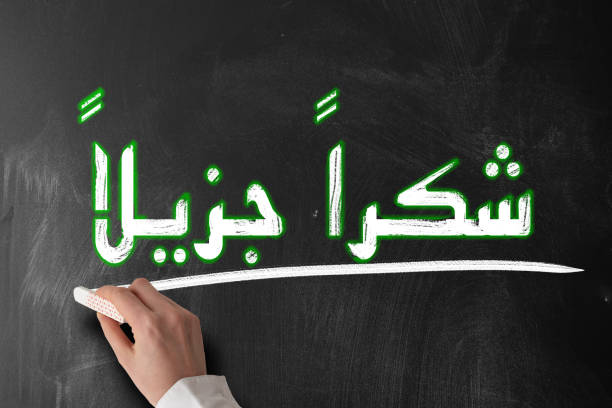 The flag of Iraq is waving in the wind, featuring three horizontal stripes of red, white, and black with green Arabic script in the center. The motion enhances the bold design and texture of the flag.