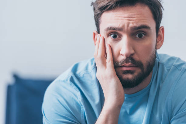 istock handsome frightened man with hand on head looking at camera at home with copy space 1144864547