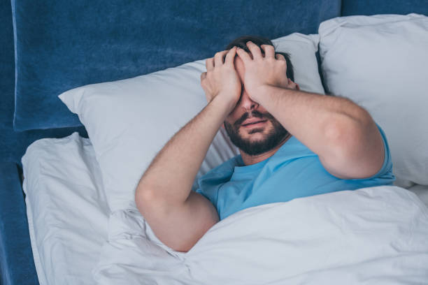 istock grieving man lying in bed, covering face with hands and crying at home 1144864991