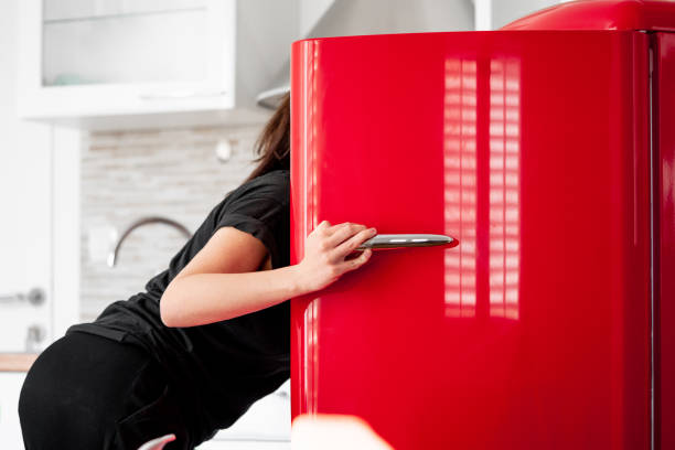 woman looking for food in red refrigerator in modern bright apartments. - domestic kitchen contemporary domestic room lifestyles imagens e fotografias de stock