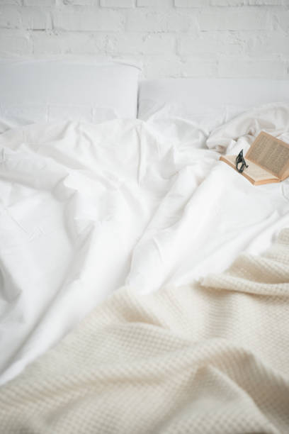 istock book and glasses on empty cozy white bed 1144867646