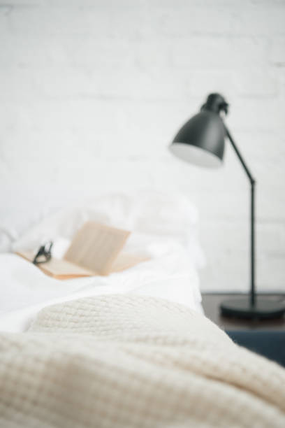istock selective focus of book and glasses on white empty bed and lamp 1144867653