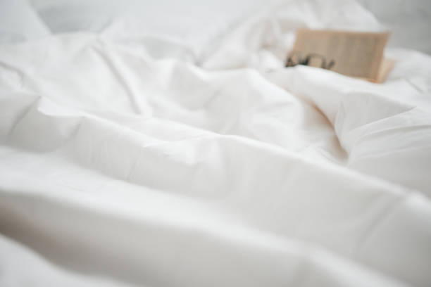 istock selective focus of book and glasses on white empty bed 1144867656