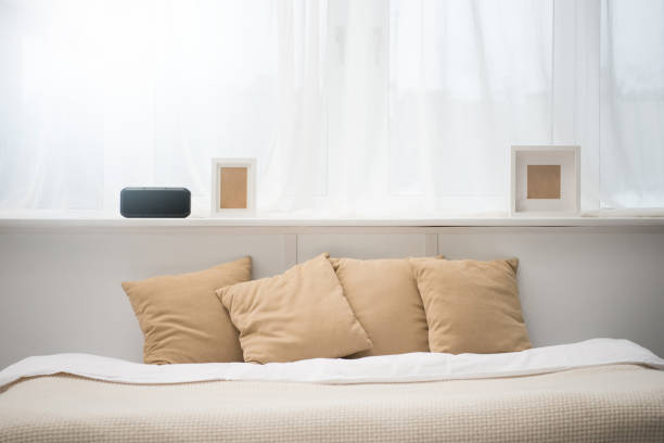 istock bedroom with brown pillows on bed, alarm clock and photo frames 1144867689
