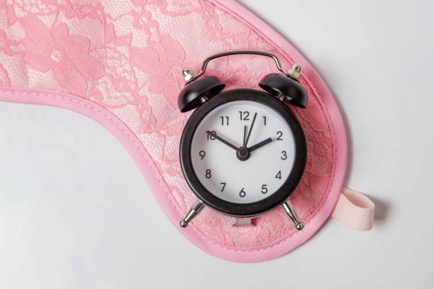 istock Sleeping mask and alarm clock on white background 1144868692