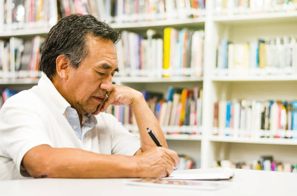 poważny starszy mężczyzna siedzący na ławce biblioteczej, piszący w swojej książce. - law library school education zdjęcia i obrazy z banku zdjęć