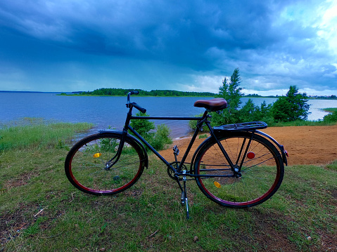 Adult road bike on the bank of a cloudy river.