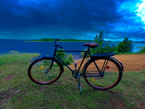 Adult road bike on the bank of a cloudy river.