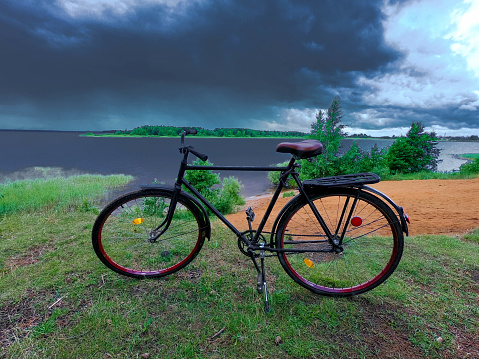 Adult road bike on the bank of a cloudy river.