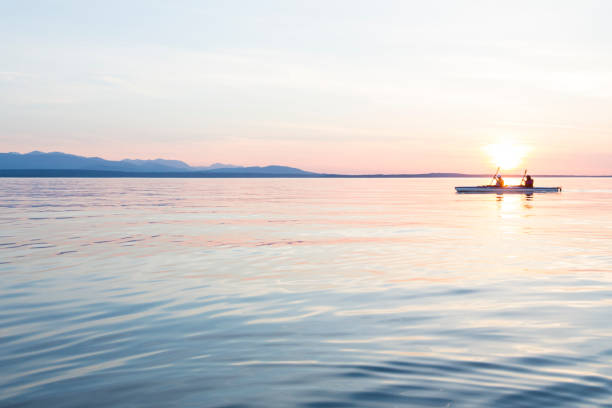 las personas mujeres kayak de mar remo barco en aguas tranquilas junto al atardecer. deportes acuáticos de aventura activa al aire libre. conceptos de viaje, destino y trabajo en equipo. - aspirations what vacations sport fotografías e imágenes de stock