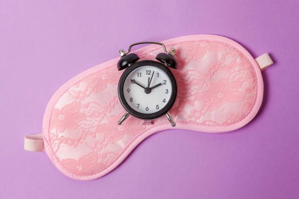 istock Sleeping mask and alarm clock on purple violet background 1144871831
