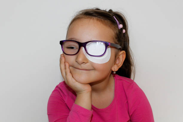 Little girl with eye patch Portrait of a little girl who is wearing an eyepatch to correct her vision, Girl with glasses and eyepatch one eyed stock pictures, royalty-free photos & images