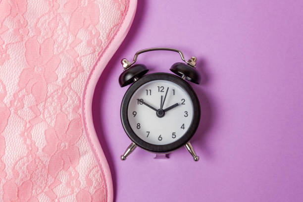 istock Sleeping mask and alarm clock on purple violet background 1144872840