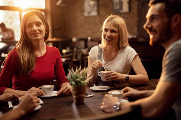 istock Young happy people drinking coffee and communicating in a cafe. 1144873192