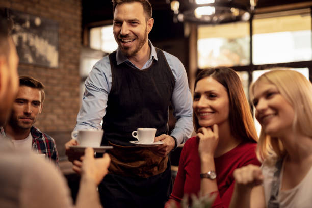 istock Happy waiter serving guests with coffee in a cafe. 1144874349