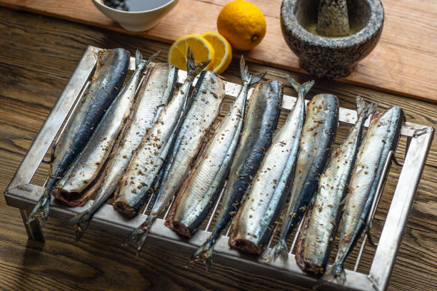 istock Raw saury on a grill for smoking with lemon and herbs top view 1144875787