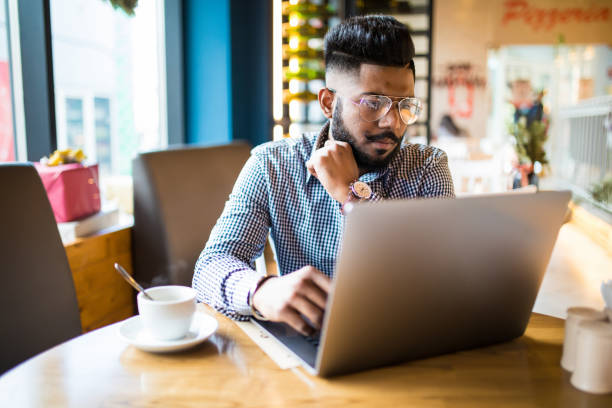 istock Indian man sitting at cafe against his laptop. 1144876085