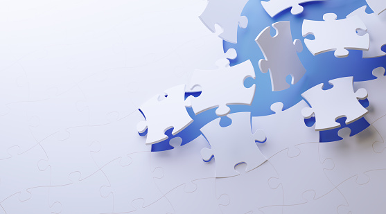 White jigsaw puzzle pieces on blue background. Horizontal composition with copy space. Great use for puzzle concepts.