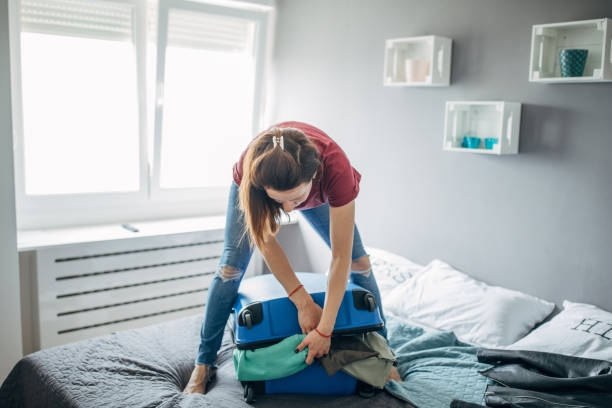 istock Young woman closing full suitcase 1144880936