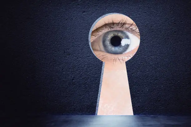 Creative keyhole opening with eye on concrete wall background. Access and vision concept