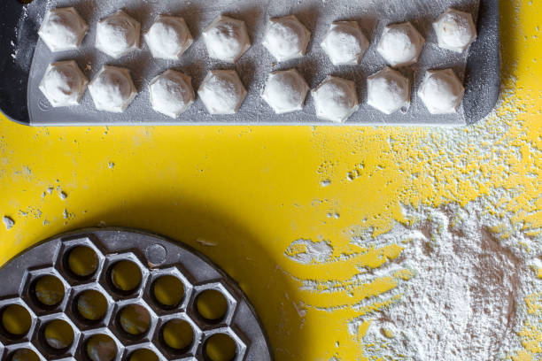 food background cooking dumplings with meat on a yellow table with form and flour top view, raw dumplings on a cutting board.