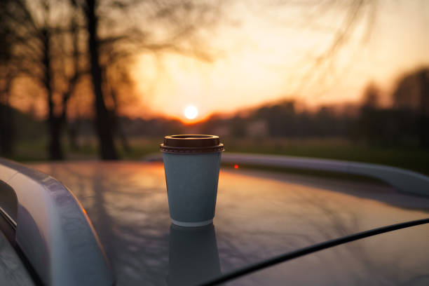café de tasse de papier au coucher du soleil restant sur un toit de voiture avec le beau bokeh de mise au point - back against the wall photos et images de collection