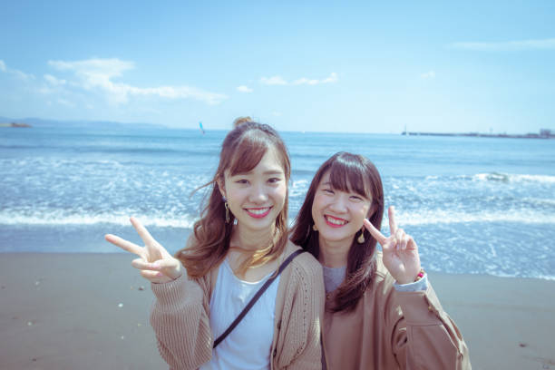 istock Young female friends making a peace sign on beach 1144884439