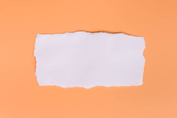 A piece of white torned paper over orange background stock photo