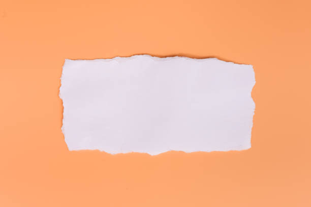 кусок белой разорванной бумаги на оранжевом фоне - torned стоковые фото и изображения