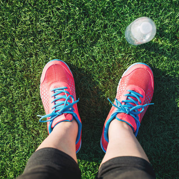 Female runner looking down at her feet in a grass field