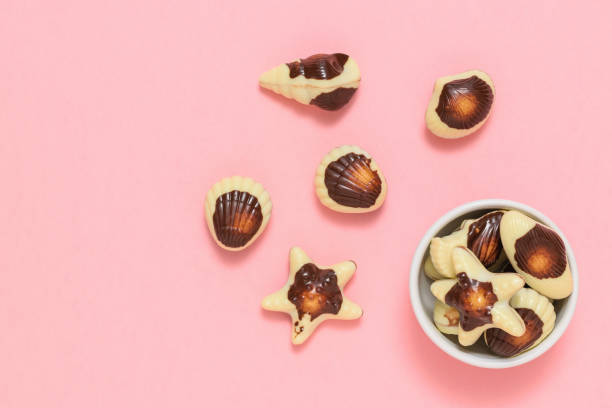 istock Chocolates in the form of sea shellfish and shells on a pink background. Flat lay. 1144926578