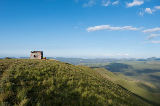 Lone Ultra runner heading up the spine of the mountain to the top in the Drakensberg. There is big peaks and mountain all around him and dark blue skies. He is very small in scale compared to his location. Big challenge ahead.