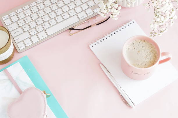 istock Pastel colors flat lay top view women's office desk . Female workspace with laptop, white flowers,  accessories, notebooks, glasses, cup of coffee on pale pink background. Copy space. 1144937607