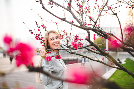 Portrait of smiling attractive woman between cherry blossom trees on springtime in Shanghai