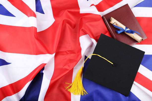 istock Graduation cap with diploma and notepad on British flag background 1144949608
