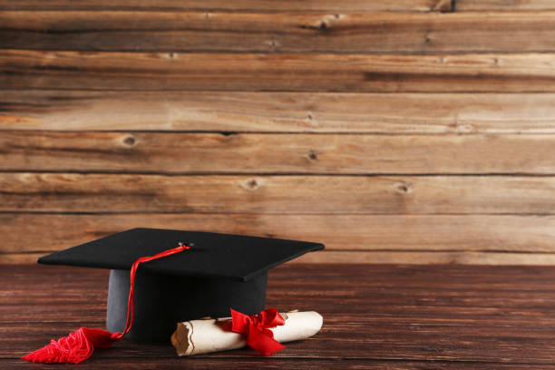 istock Graduation cap with diploma on brown wooden table 1144949704