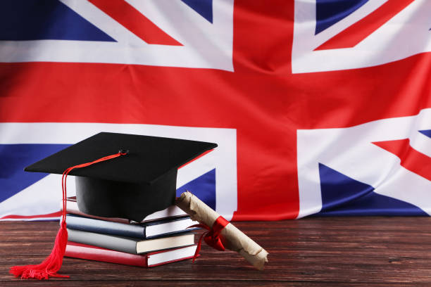 istock Graduation cap with diploma and stack of books on brown wooden table 1144949738