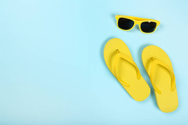 istock Pair of flip flops with sunglasses on blue background 1144951885