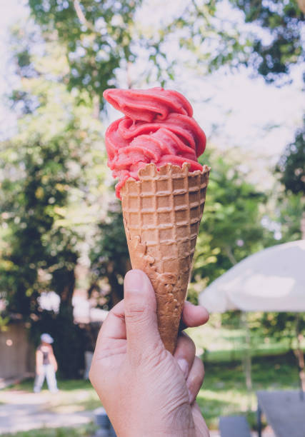 istock Hand holding ice cream cone with green garden background 1144953368