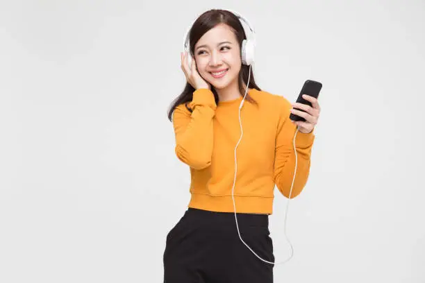 Photo of Beauty young Asian woman listening music with headphones in playlist song application on smartphone