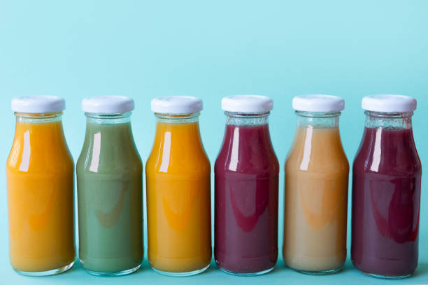 istock Different fruit and vegetable juice bottles isolated on blue background 1144957881
